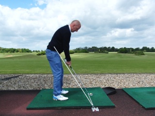 Golf instructor demonstrating Swing Plane Perfector on range mat